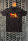 Bad Brains Rasta Lion black t-shirt featuring artwork of their rasta lion imagery in red and yellow with the band name in large black font outlined in red on a green background below the image, displayed on a metal gate background.
