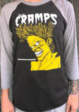 The Cramps Bad Music for Bad People heathered black raglan t-shirt with heathered grey 3/4 sleeves featuring album artwork, on a model in front of a metal gate background.