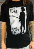 The Cure Boys Don't Cry black t-shirt featuring album artwork, on a model against a metal gate background.