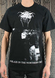 Darkthrone A Blaze in the Northern Sky black t-shirt featuring album artwork, on a model against a metal gate background.