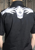 Back of black button down work shirt featuring large black and white image of Elvira looking surprised across the upper back, on a model against a metal gate background.