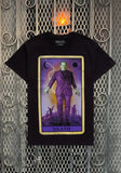 Frankenstein Death Tarot Card black t-shirt featuring a colorful image of the death tarot card with Frankenstein on it, displayed on a metal gate background.