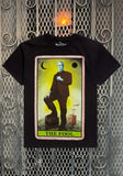 Herman Munster The Fool Tarot Card black t-shirt featuring a colorful image of the fool tarot card with Herman Munster on it, displayed on a metal gate background.