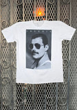 Freddie Mercury white t-shirt featuring a large black and white headshot of him wearing sunglasses with the text 'Freddie' in white on the top of the image, displayed on a metal gate background.