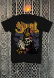 Ghost New Pope black t-shirt featuring the band name logo in yellow and burgundy text along with an illustration of a pope holding the Ghost logo in his prayer hands, displayed on a metal gate background.