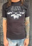 Glenn Danzig Logo black t-shirt featuring the black and white horned skull logo along with the word 'Glenn' in the classic logo lettering, on a model in front of a metal gate.