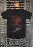 Gojira Volcano black t-shirt featuring a large band logo in red font and black and purple volcano erupting artwork, displayed on a metal gate background.