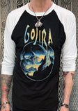 A person wearing a black and white 3/4 sleeve raglan t-shirt with a 'Gojira' band graphic of a sea creature on the front.