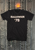 Front of Halloween '78 black t-shirt featuring the text 'Halloween '78' in white with orange outline, displayed against a metal gate background.