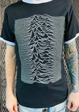 Joy Division Ringer black t-shirt with white trim on neck and sleeves featuring unknown pleasures album artwork, on a model against a metal gate background.
