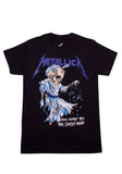Front of Metallica Harvester of Sorrow black t-shirt featuring an illustration of the Harvester along with the band logo across the top in purple and the text 'their money tips her scales again' in white on the lower left, displayed on a white background.