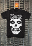 Misfits Crimson Ghost black t-shirt featuring a large band logo in white outline along with a large image of their Crimson Ghost in white, displayed on a metal gate background.