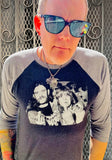 Ozzy Osbourne and Lemmy Kilmister black raglan t-shirt with heather grey 3/4 sleeves featuring a black and white image of them sticking up their middle fingers, on a model against a metal gate background.
