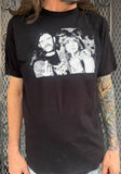 Black Ozzy Osbourne and Lemmy Kilmister t-shirt featuring a black and white image of both of them sticking up their middle fingers, on a model against a metal gate background.