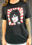Siouxsie and the Banshees Japanese Rising Sun black t-shirt featuring an illustration of her face in front of a red and white rising sun stripe design with the 'Siouxsie' logo in white in the lower left corner of the image, on a model against a metal gate background.