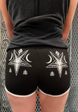 Black fitted shorts with white trim and a white Baphomet star graphic on each side, shown on a model from behind.