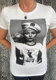 Debbie Harry Blondie Popeye Salute white t-shirt featuring an image of Debbie wearing a t-shirt with an image of Popeye on it while she salutes, photographed on a model in front of a metal gate.