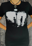 The Cure Exorcist black t-shirt with image of Robert Smith holding a guitar in style of the movie The Exorcist, photographed on a model in front of a metal gate background.