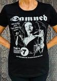 The Damned Vampira black t-shirt featuring the artwork from the movie with the band logo in white, photographed on a model in front of a metal gate background.