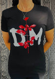 A person wearing a black short-sleeve t-shirt with a large white 'DM' graphic and a red rose design on the front, standing in front of a metal mesh gate.