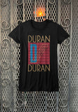Duran Duran Seven and the Ragged Tiger black t-shirt featuring the album artwork, photographed flat on a metal gate background.