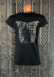 Morticia Addams black t-shirt featuring an image of her sitting in a chair fashioned after a ribcage, photographed flat on a metal gate background.