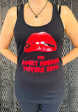 Rocky Horror Picture Show black tank top featuring the movie name and lips artwork, photographed on a model in front of a metal gate background.