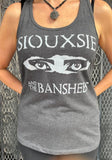 Siouxsie and the Banshees grey tank top featuring the iconic eyes logo, photographed on a model in front of a metal gate background.
