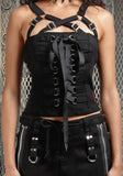 A black strappy corset top with front lacing and buckle details, shown on a model against a fence background.