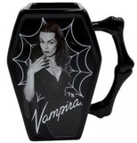 Close-up of black coffin-shaped ceramic mug with a handle, featuring a vintage-style black and white graphic of Vampira with a spiderweb design and the word 'Vampira' in white script.