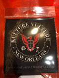 Kulture Vulture logo black coozie featuring the vulture logo in red and the words 'Kulture Vulture New Orleans' along with the website URL in white text, photographed inside the clear cellophane packaging.