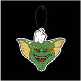 Close-up of Gremlins car air freshener featuring the green and yellow head of Stripe with his white tuft of hair sticking up.