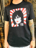 Siouxsie and the Banshees Japanese Rising Sun black t-shirt featuring an illustration of her face in front of a red and white rising sun stripe design with the 'Siouxsie' logo in white in the lower left corner of the image, on a model.