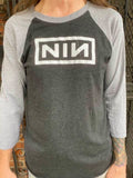 Nine Inch Nails heathered black raglan t-shirt with grey 3/4 sleeves featuring the NIN logo, photographed on a model.