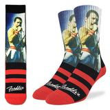 Crew socks featuring an image of Freddie Mercury wearing a white jumpsuit and singing, with red and black stripes on the feet and the word "Freddie" in script, photographed on a white background.