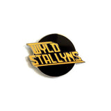 Close-up of Bill & Ted circular black enamel pin featuring the words 'WYLD STALLYNS' in bold yellow lettering with black outlines, photographed on a white background.